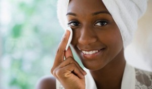 Black woman wiping face with cotton pad